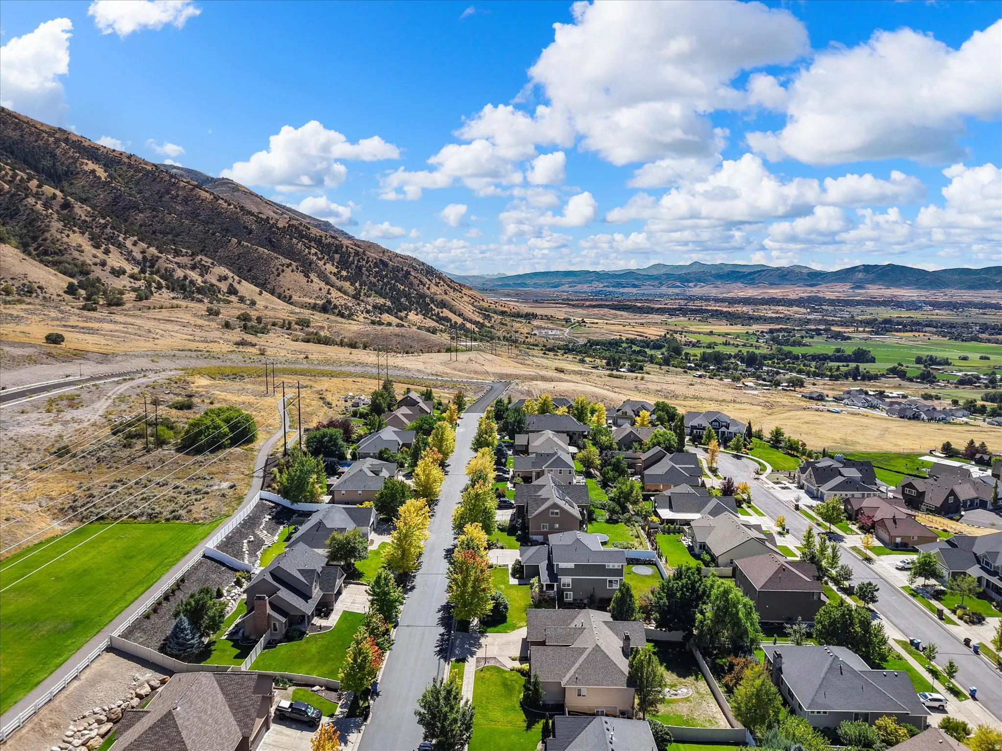 Expansive mountain backdrop, established neighborhood with mature trees, paved streets, and varied residential architecture