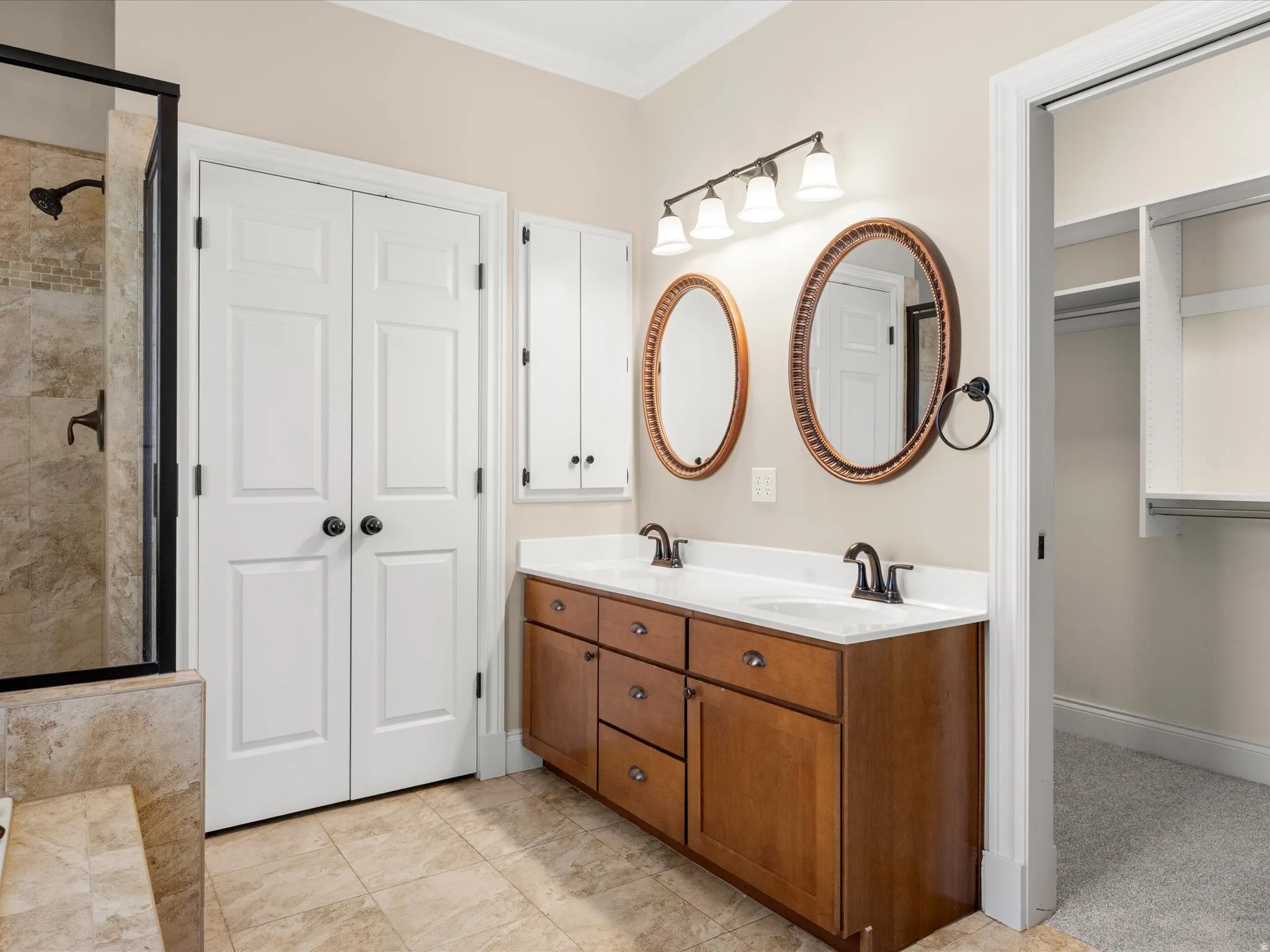 Dual vanity with white countertops, tiled flooring, and an adjacent walk-in shower with tiled walls