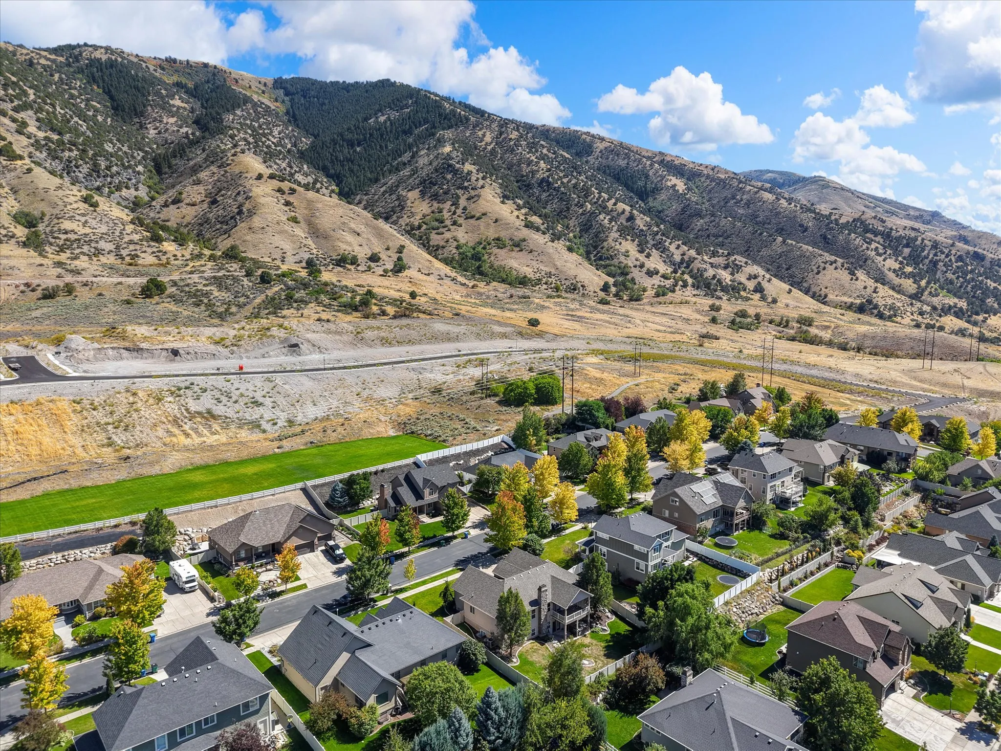 Residential development with varied architectural styles and mature landscaping, set against a mountainous backdrop
