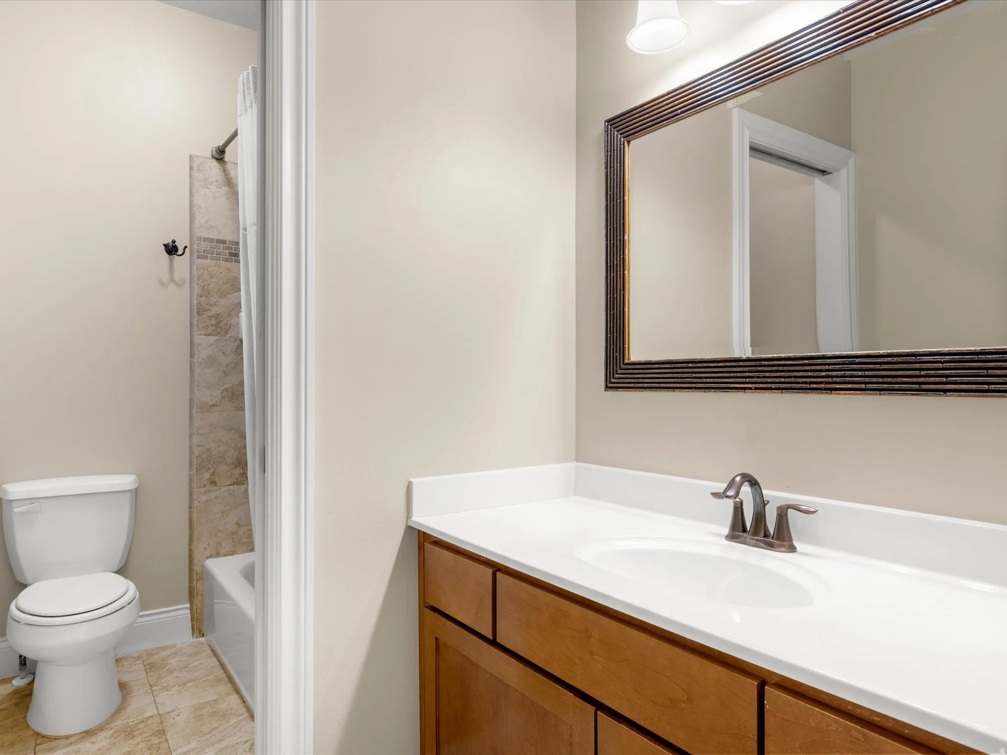 Bathroom featuring a wood-finish vanity with a white countertop, an oval undermount sink, and a framed mirror