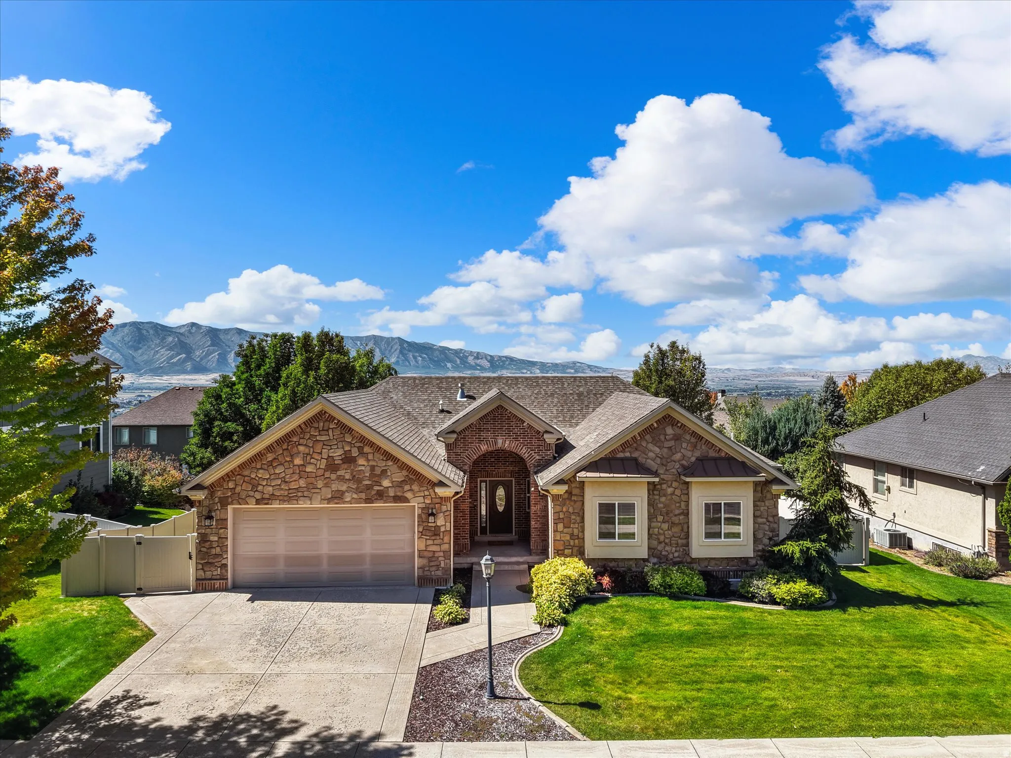 Stone veneer exterior with an arched entryway, double garage, and a concrete driveway