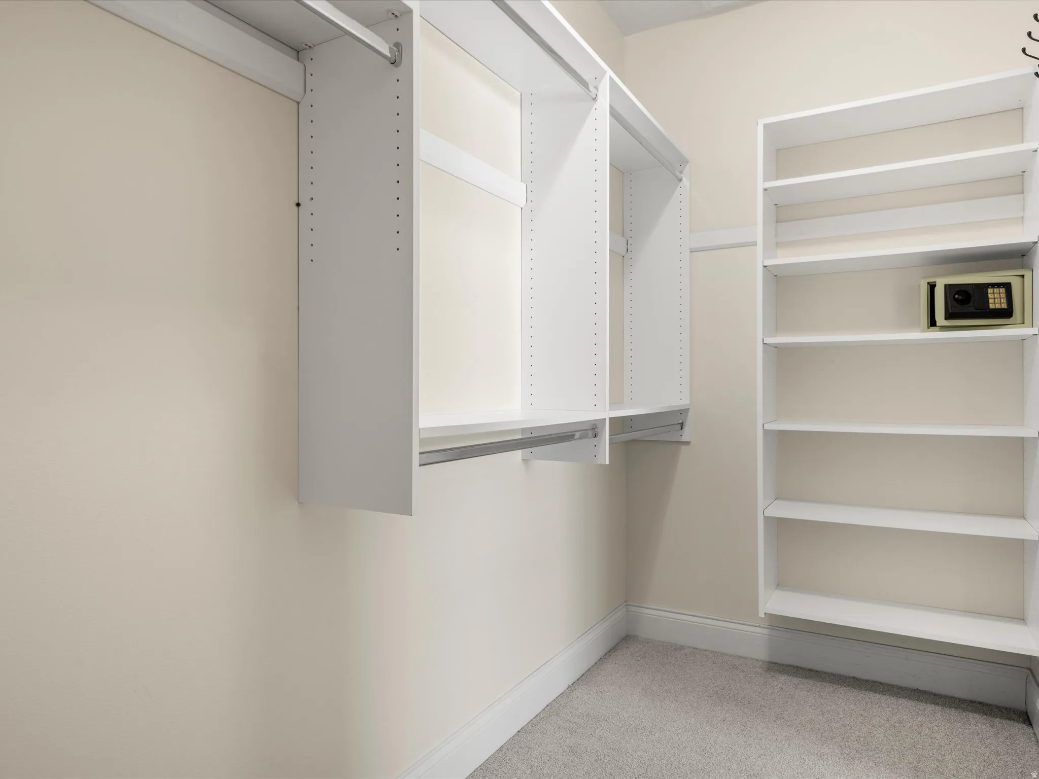 Custom closet system with multiple hanging rods, adjustable shelving, and a built-in safe