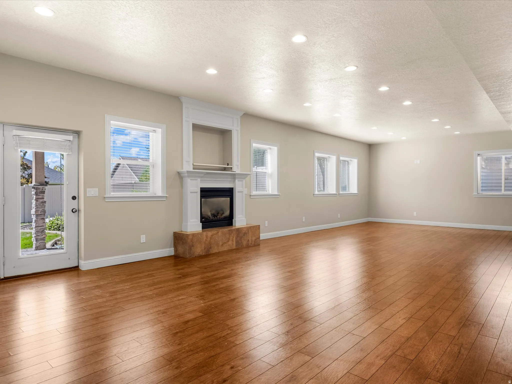 Spacious interior with wood-finish flooring, recessed lighting, a built-in fireplace, and multiple windows