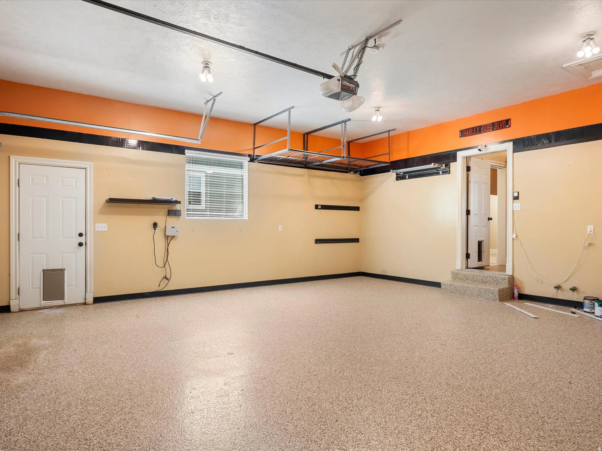 Garage with epoxy-coated flooring, overhead storage racks, and a single window with blinds