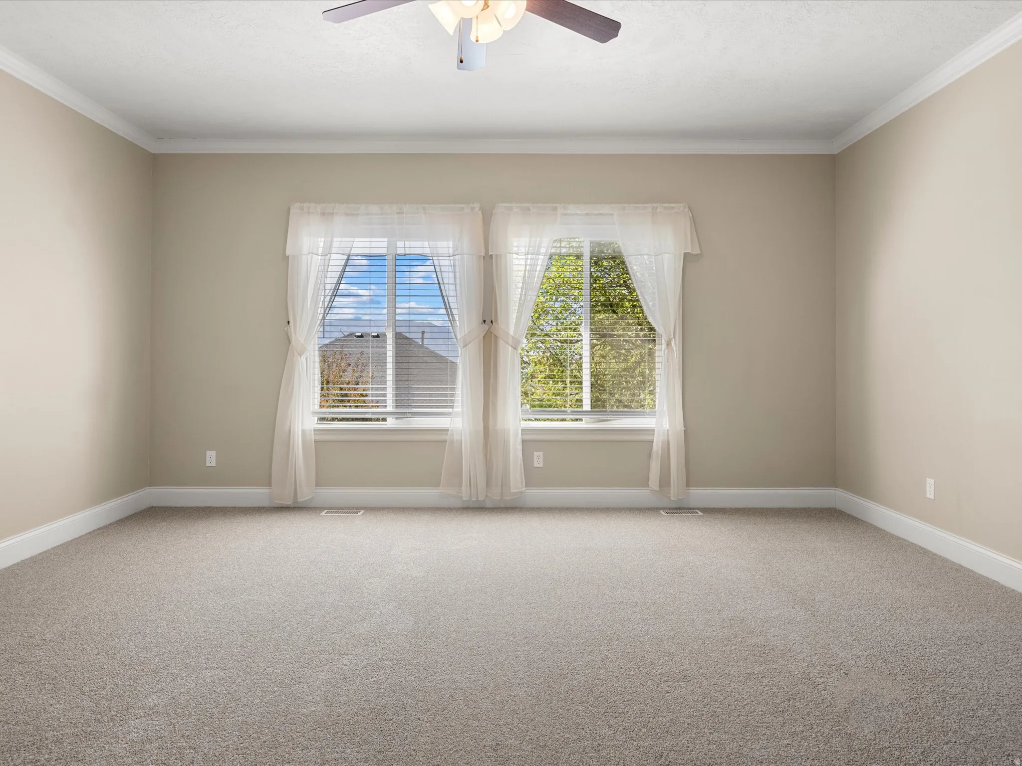 Recessed windows with blinds, crown molding, ceiling fan, and neutral-toned carpeting