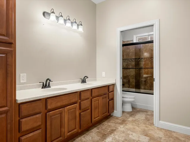 Dual vanity with light-colored countertop, wood-finish cabinetry, and matte black fixtures