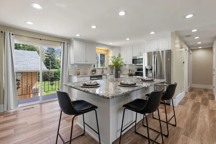 White cabinetry with upper and lower storage, white subway tile backsplash, and stainless steel appliances