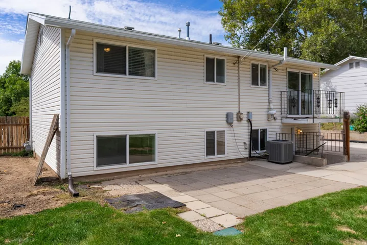 Rear exterior featuring a patio, sliding glass door, and a second-story balcony with metal railing