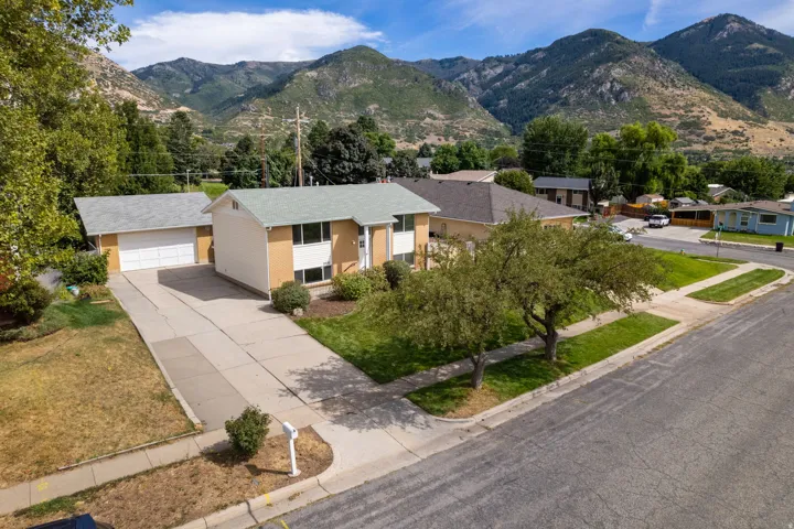 Mountain backdrop, attached two-car garage, established front yard landscaping, paved driveway, and sidewalk