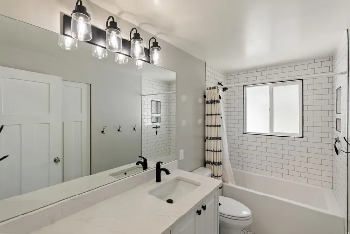 Extended vanity with a white countertop and integrated sinks, matte black faucets, and a large wall-mounted mirror