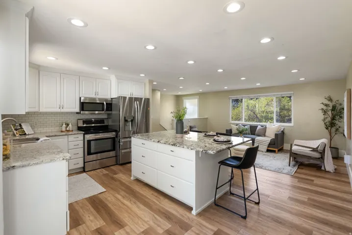 Open-concept living space with wood-finish flooring, recessed lighting, and large windows