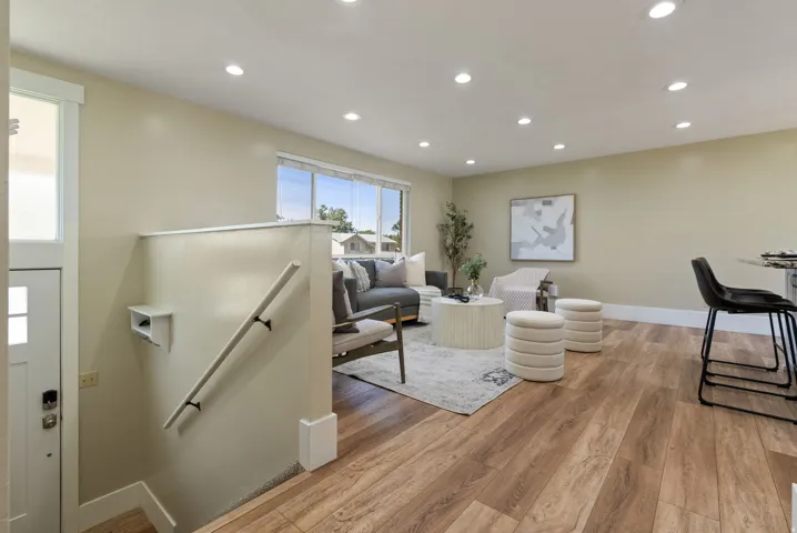 Wood-finish flooring, recessed ceiling lighting, abundant natural light, and a built-in stair handrail