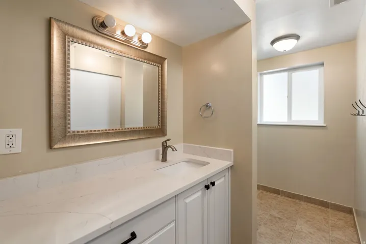 White vanity with shaker-style cabinetry, an integrated sink, and a light-toned countertop