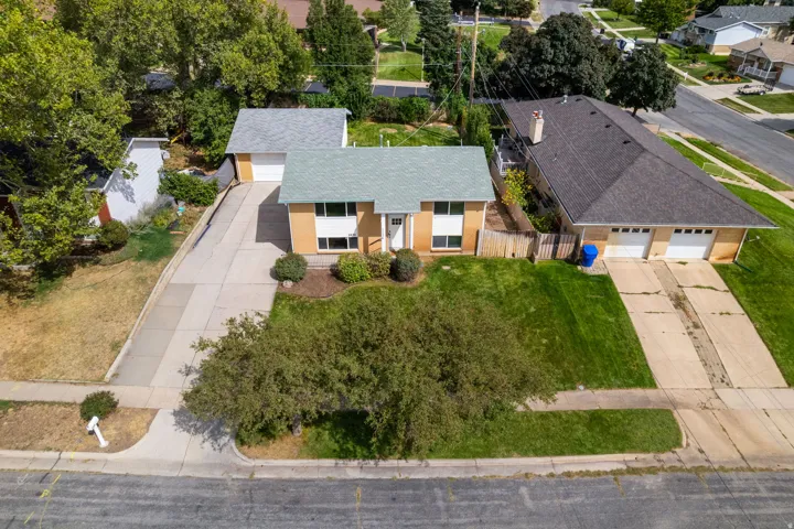 Property featuring a split-level design, attached single-car garage, mature front yard landscaping, concrete driveway, and a fenced side yard