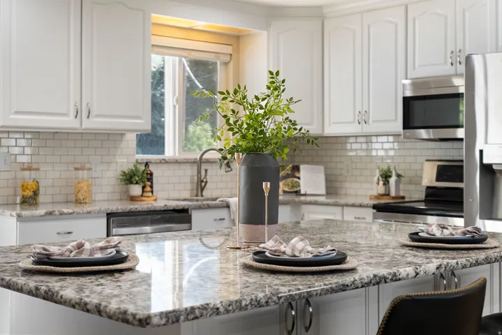 Kitchen featuring a center island, white cabinetry, a subway tile backsplash, stainless steel appliances, and a window with natural light