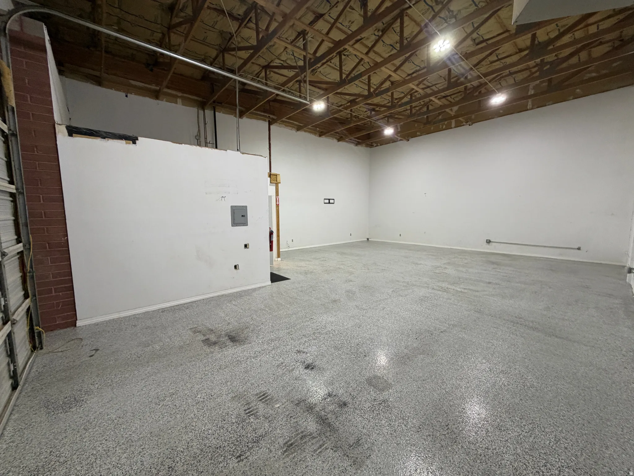 Exposed wood beam ceiling with recessed lighting, painted white walls, and a light gray speckled floor
