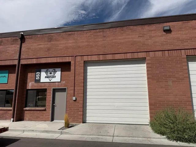 Brick exterior with a large roll-up door, a separate pedestrian entrance, and an overhead lighting fixture
