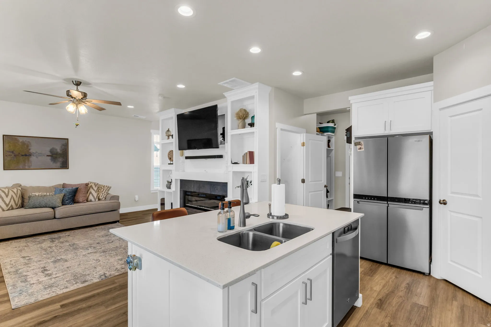 Kitchen island with double basin stainless steel sink, integrated dishwasher, and white cabinetry