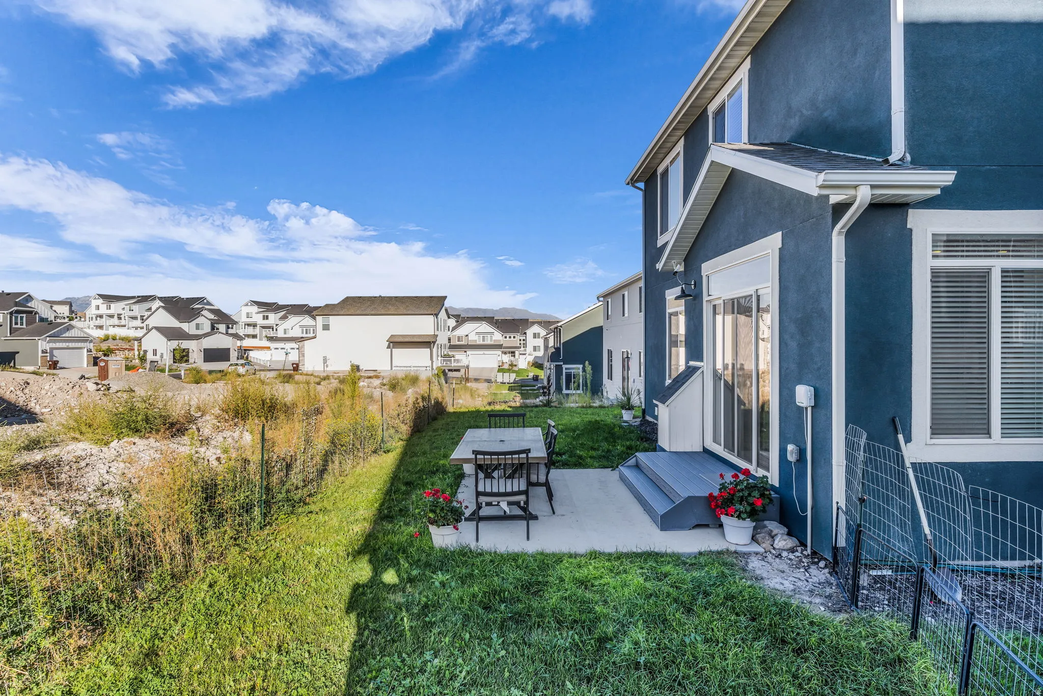 Blue stucco exterior with white trim, a sliding glass door, and a concrete patio