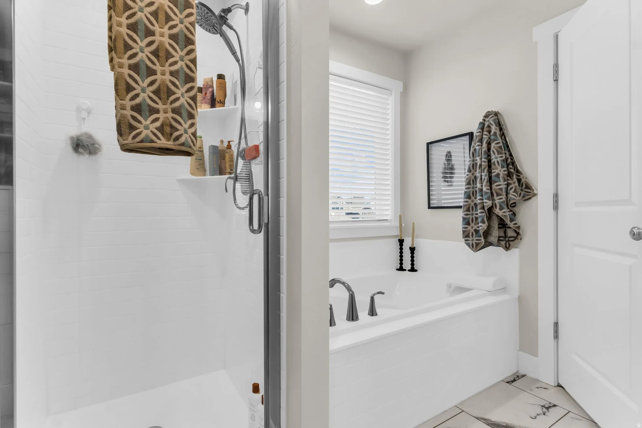 Built-in soaking tub with deck-mounted faucet, shower with white subway tile surround, clear glass shower enclosure, and light-toned flooring