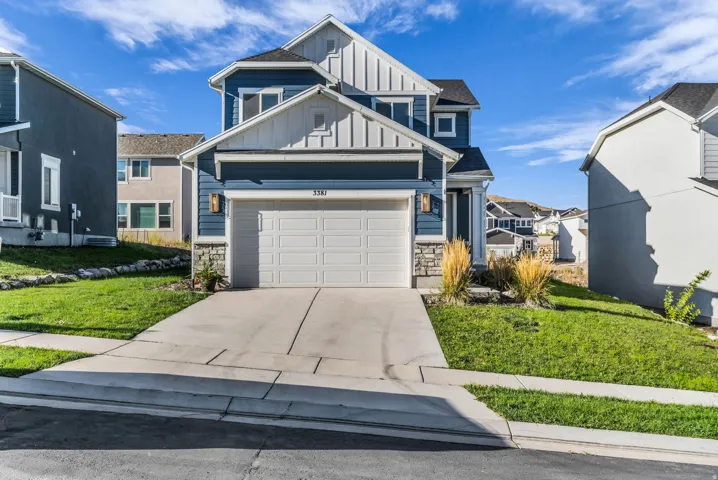 Two-story residence featuring blue siding with white trim, a two-car garage, and a concrete driveway