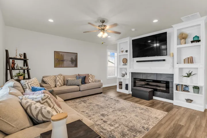 Living area featuring wood-finish flooring, a ceiling fan, recessed lighting, and a built-in media center with shelving surrounding an electric fireplace