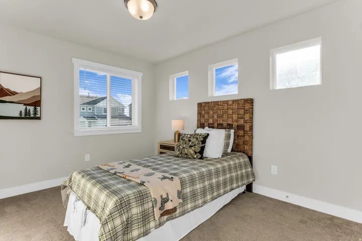 Neutral wall paint, carpet flooring, a large window with blinds, and two square transom windows