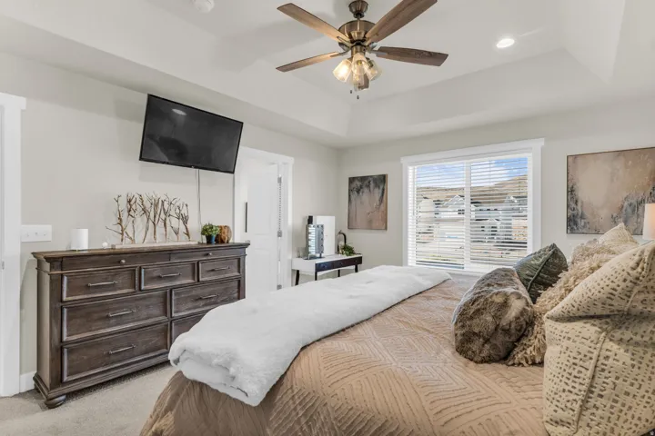 Tray ceiling, ceiling fan with light fixture, recessed lighting, large window with blinds, and carpeted flooring