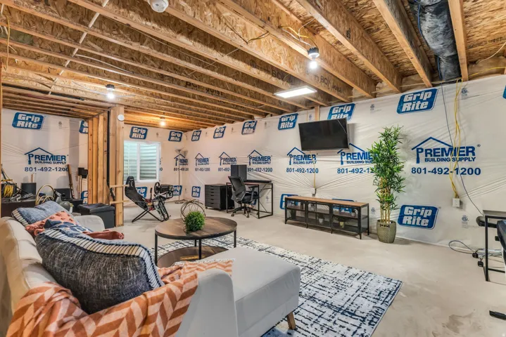 Unfinished basement area. Five electrical outlets installed and overhead LED light - featuring exposed ceiling joists and a visible window well