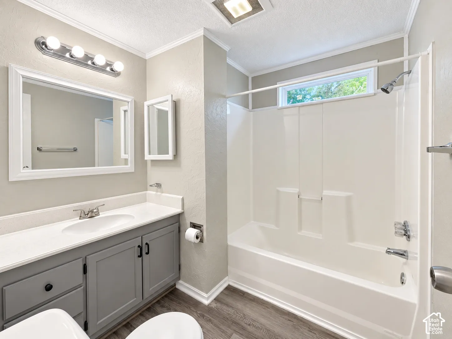 White vanity countertop with an integrated sink, gray wood-finish cabinetry, and wood-finish flooring