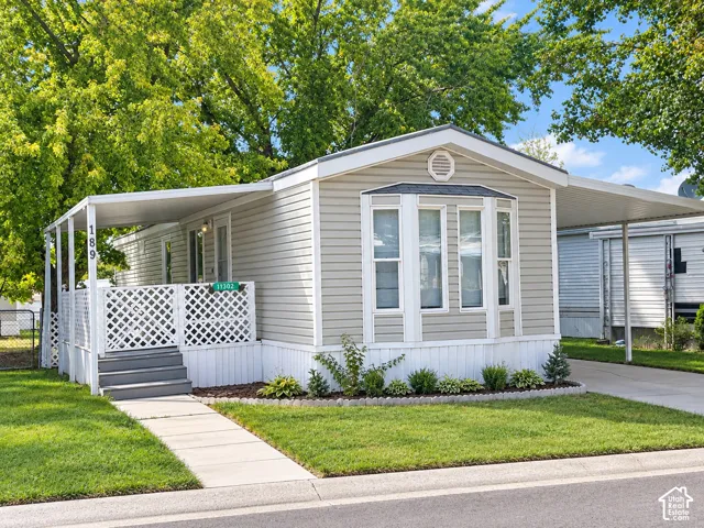 Light-toned siding exterior with a covered porch, bay window, and covered parking