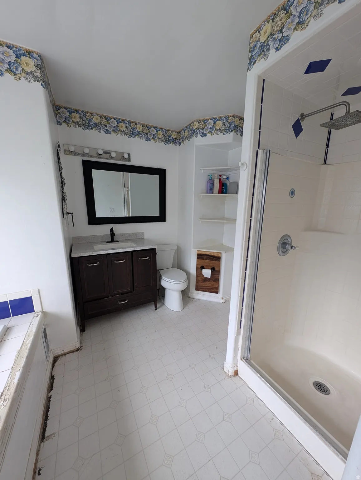 Bathroom featuring a dark wood finish vanity with a white countertop, a framed mirror, and built-in shelving