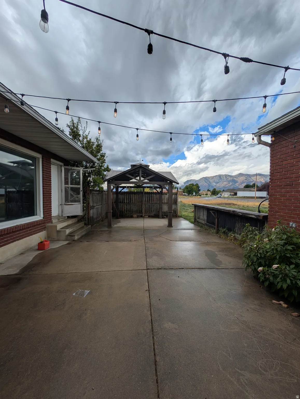 Expansive concrete patio area featuring string lighting and a covered gazebo