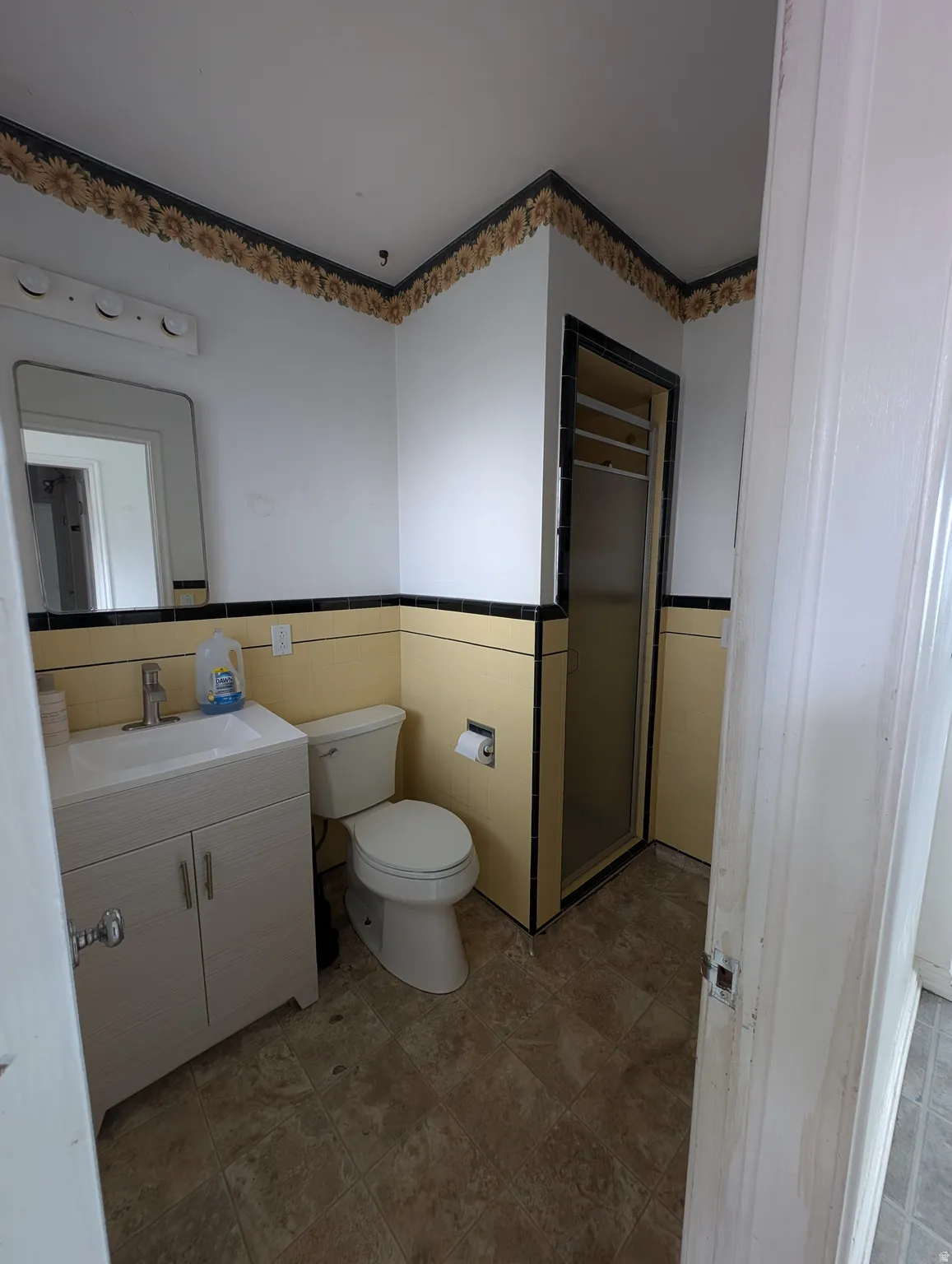 White vanity with integrated sink, toilet, and stand-up shower with glass enclosure
