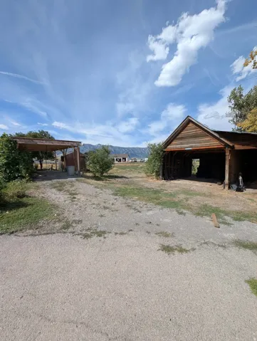 Expansive gravel area with a covered carport and an open-sided outbuilding