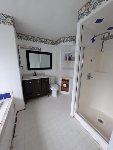 Bathroom featuring a dark wood finish vanity with a white countertop, a framed mirror, and built-in shelving