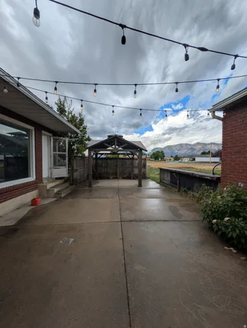 Expansive concrete patio area featuring string lighting and a covered gazebo