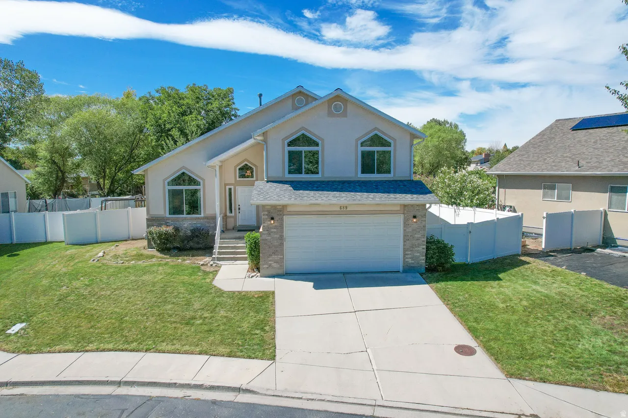 Two-story stucco exterior with arched windows, stone facade accents, and an attached two-car garage