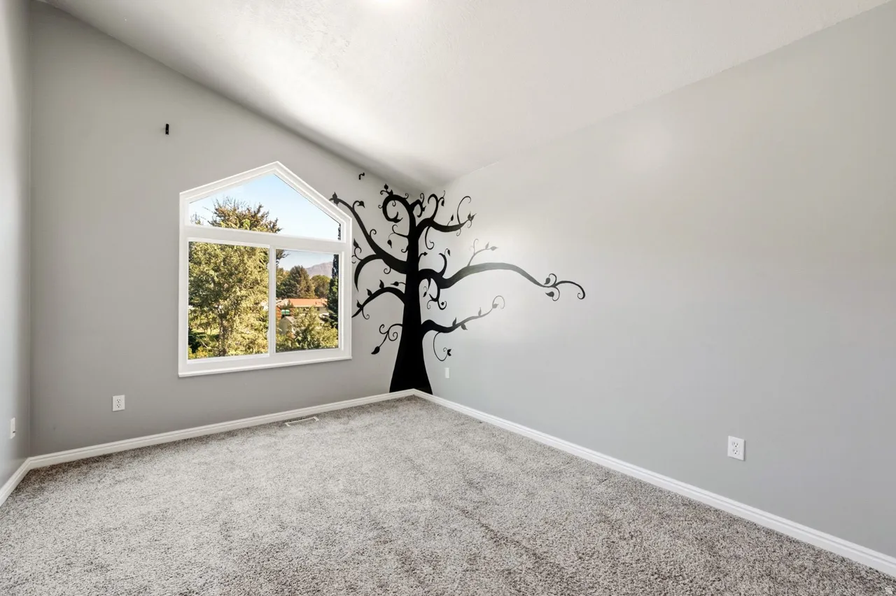Vaulted ceiling with a large arched window, gray carpeting, and light gray wall finishes