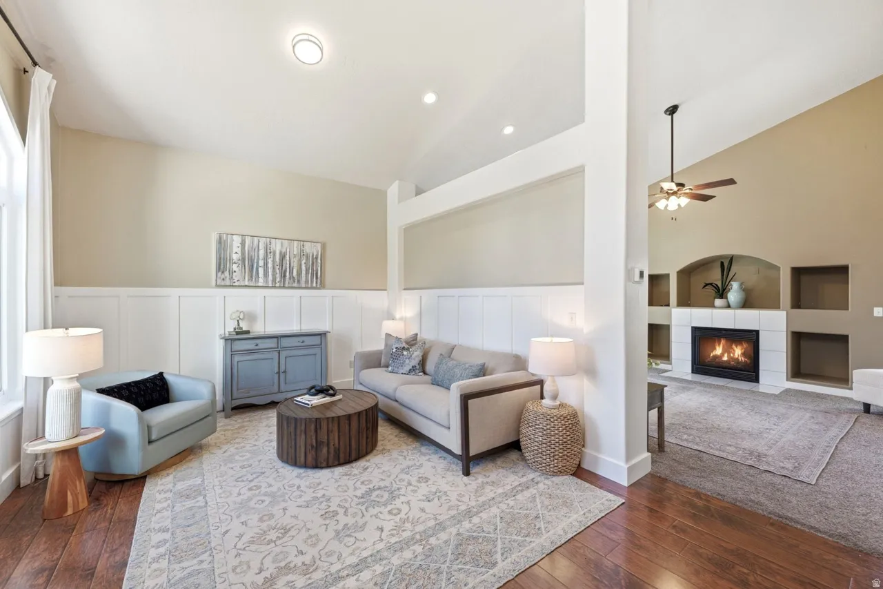 Vaulted ceilings, wood-finish flooring, white wainscoting, recessed lighting, and a tiled fireplace surround with built-in shelving