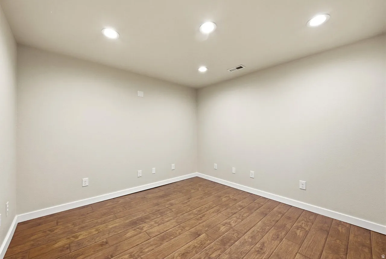 Wood-finish flooring with white trim, recessed lighting, and neutral wall tones