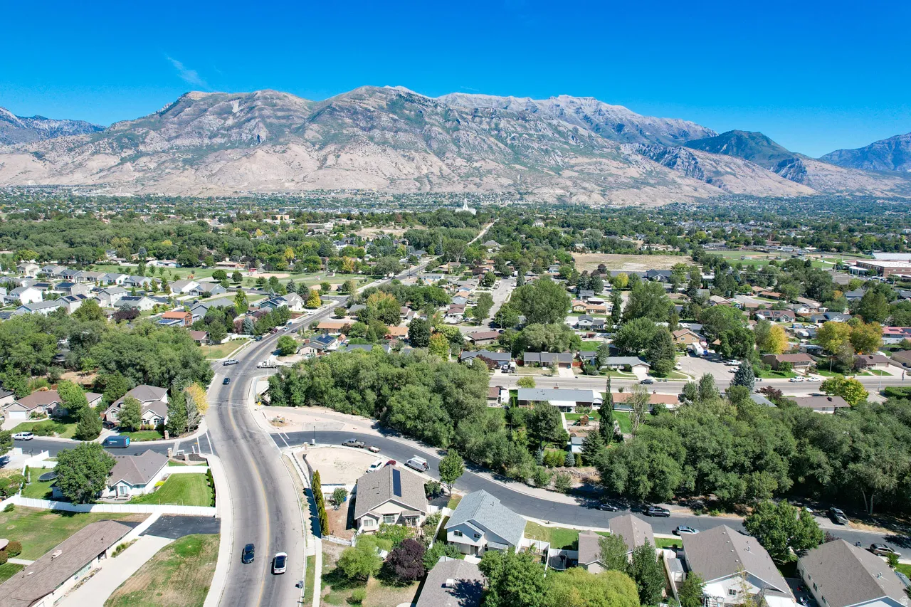 Expansive residential area featuring established homes, mature trees, a clear road network, and a prominent mountain backdrop