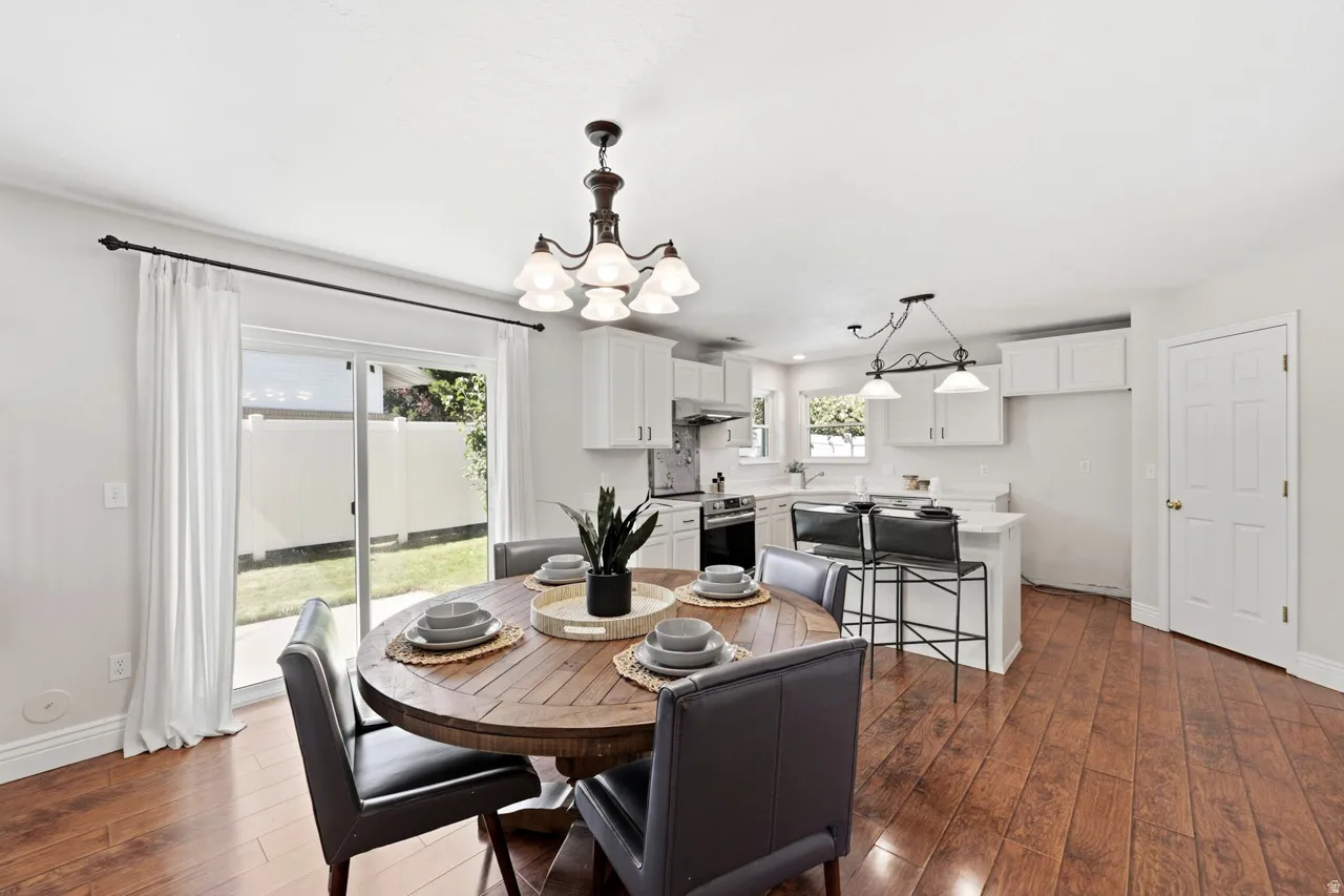 Wood-finish flooring throughout, white kitchen cabinetry, stainless steel appliances, and a sliding glass door to the exterior