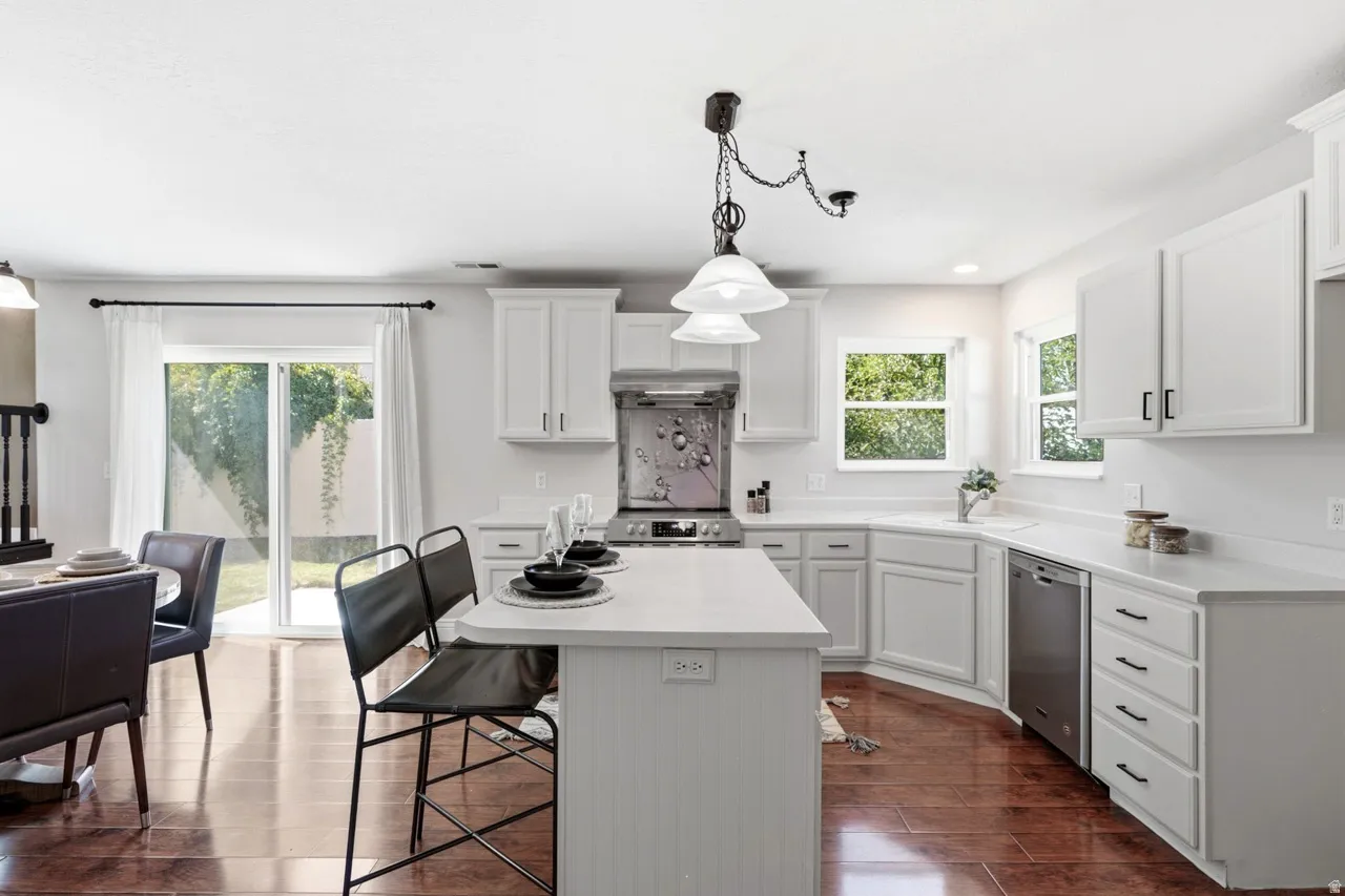 White shaker cabinetry, light-toned countertops, stainless steel appliances, wood-finish flooring, and a sliding glass door