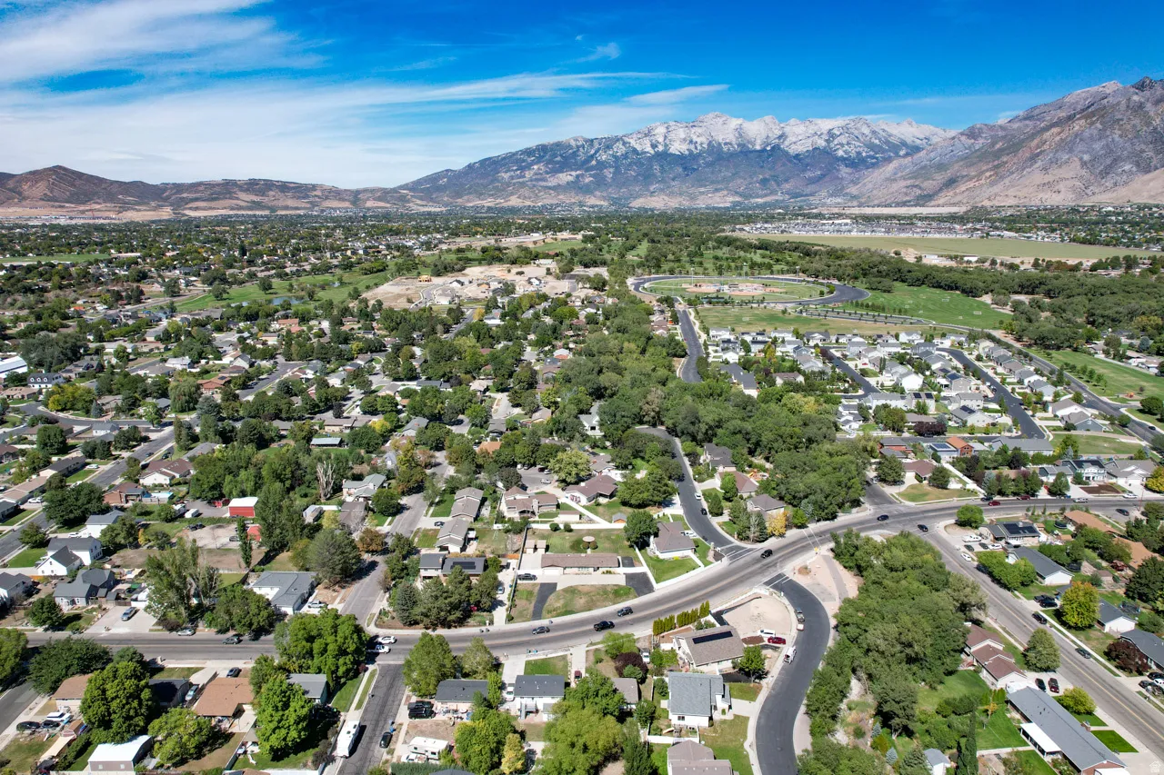 Expansive neighborhood with mature trees, established residential properties, prominent roadways, and distant snow-capped mountains
