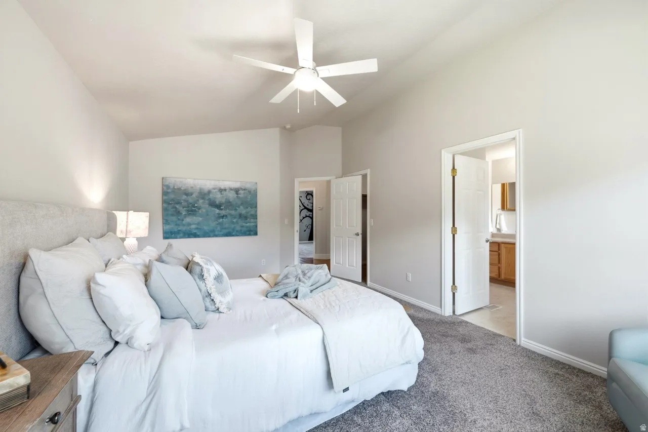 Vaulted ceiling featuring a ceiling fan, light gray wall paint, and gray carpeting