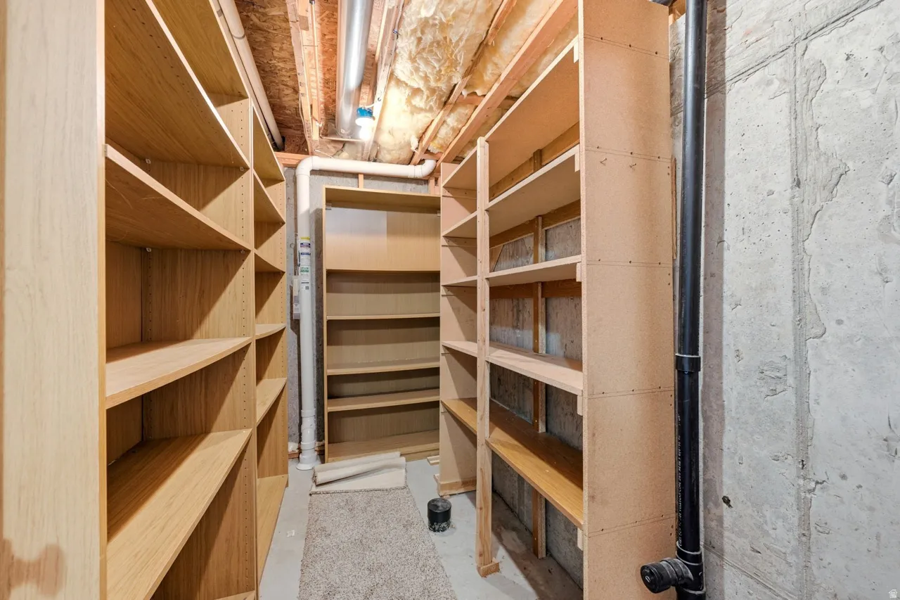 Extensive shelving system with adjustable wood-finish shelves and exposed concrete wall