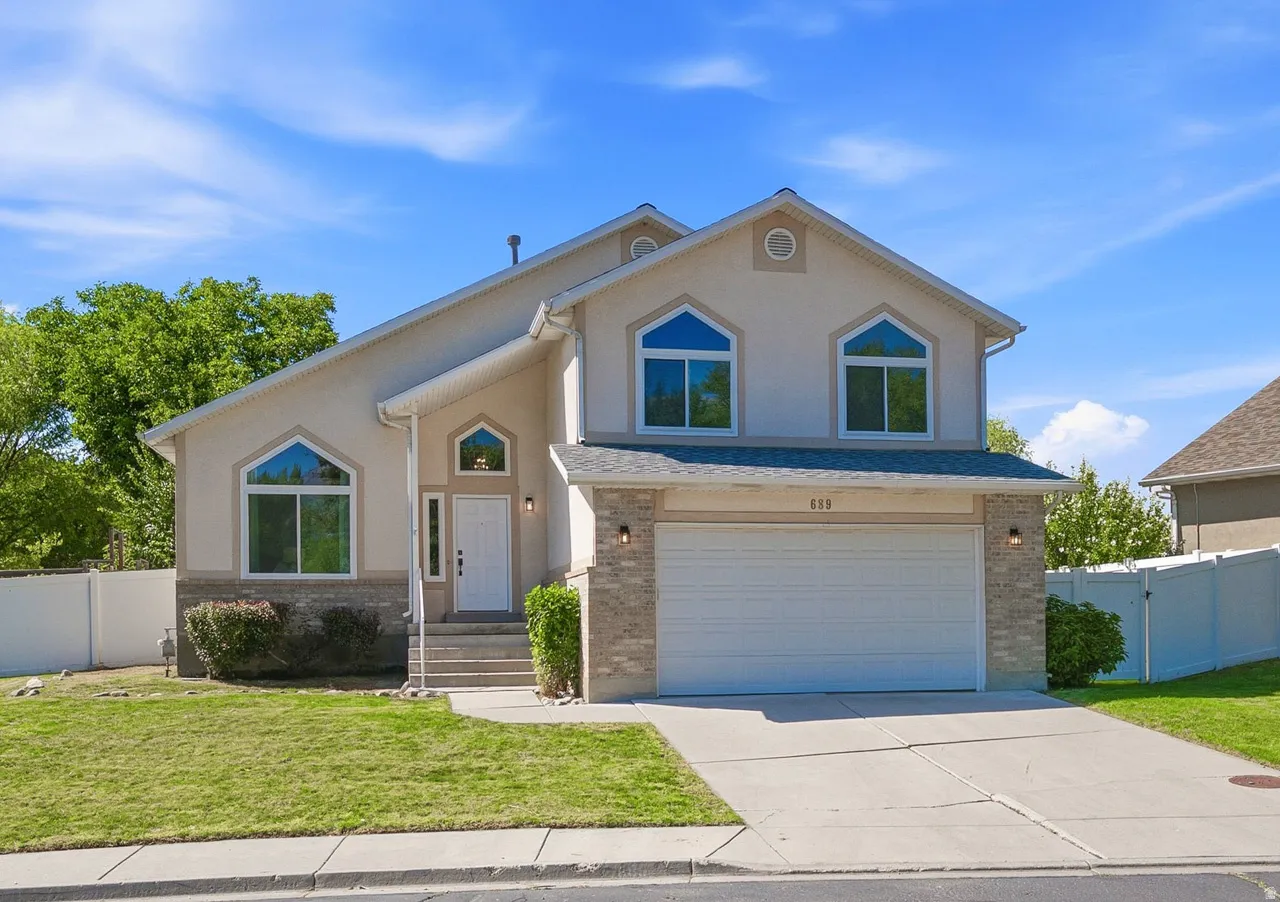 Two-story stucco exterior with decorative stone accents, arched windows, an attached two-car garage, and a concrete driveway