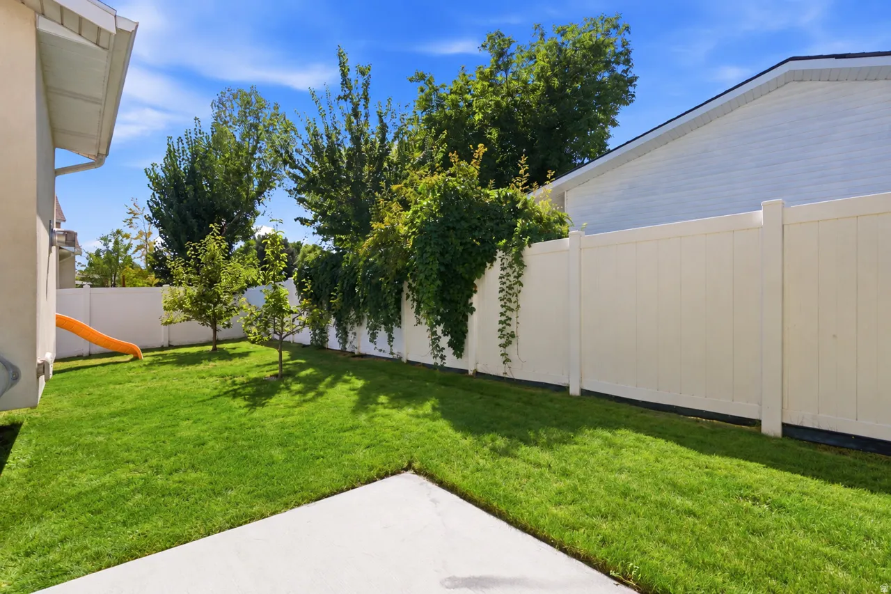 Expansive backyard featuring a well-maintained lawn, mature trees, and a privacy fence