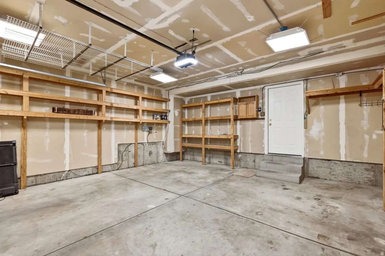 Concrete flooring with a built-in shelving system, overhead storage racks, and task lighting